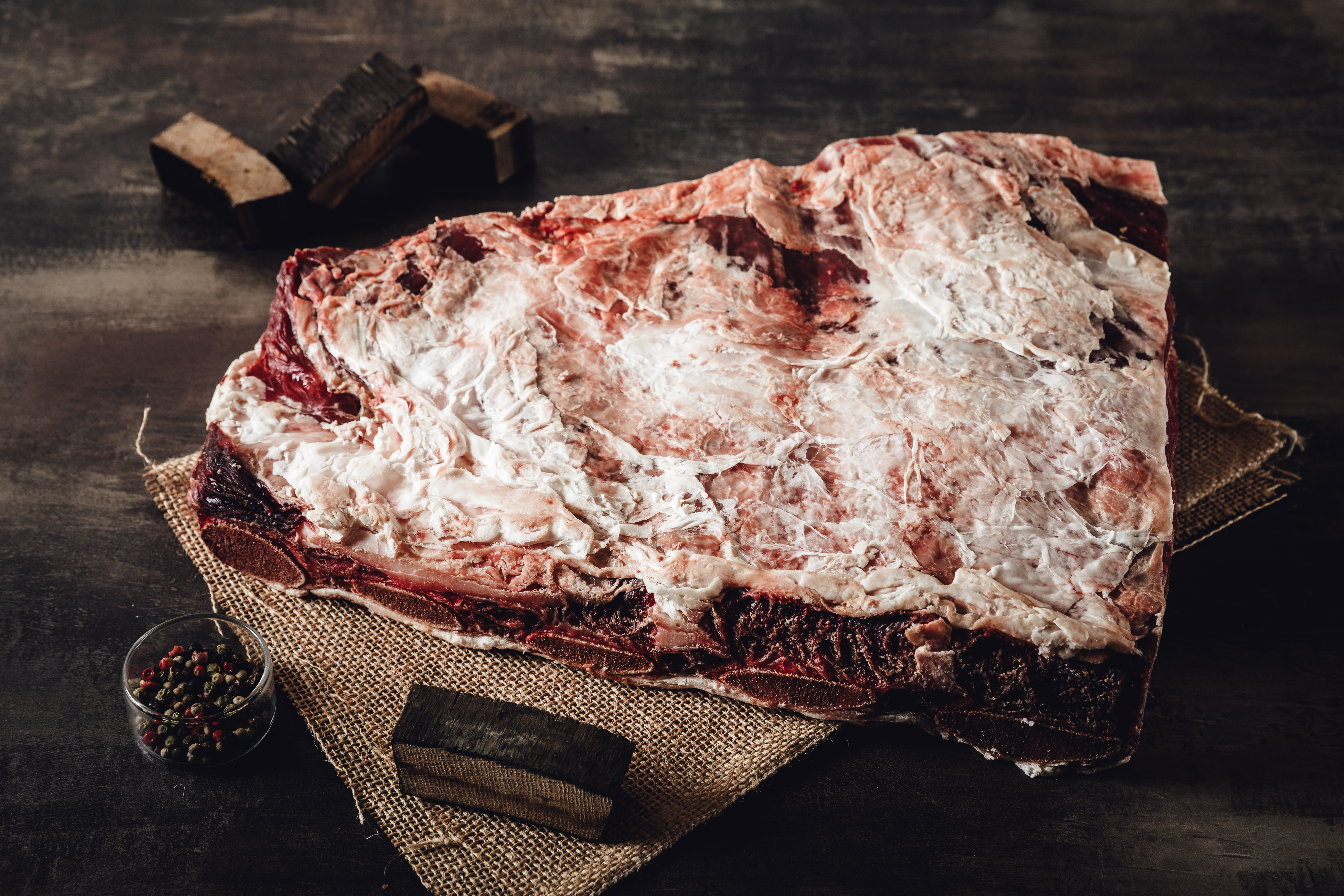 Ein hochwertiges mariniertes Oberpfalz-Beef Steak auf einem rustikalen Holzbrett, umgeben von frischen Kräutern und Gewürzen, präsentiert die erstklassige Fleischqualität aus der Oberpfalz.