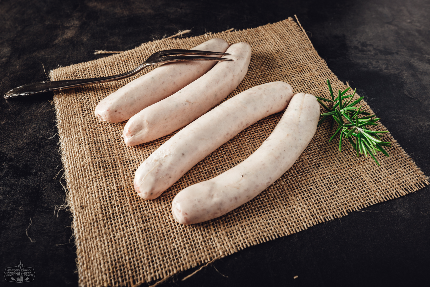 Geflügelbratwurst fein - saftige, helle Bratwurst aus Geflügelfleisch, perfekt für den Grill oder die Pfanne, auf einem Holzbrett präsentiert.