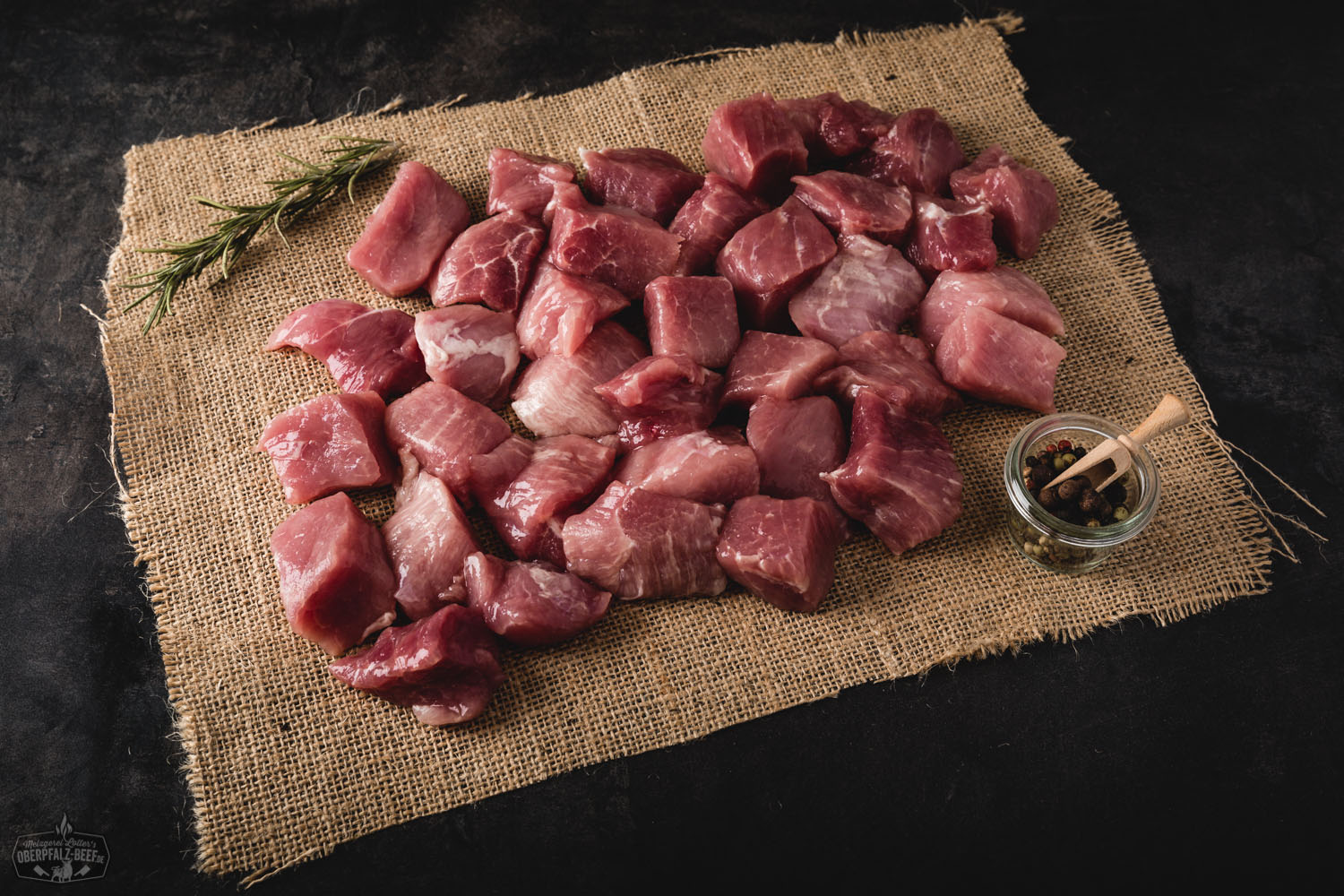 Handgeschnittenes Gulasch vom Oberpfälzer Landschwein in naher Ansicht auf einem weißen Hintergrund. Saftige Fleischstücke frisch serviert.