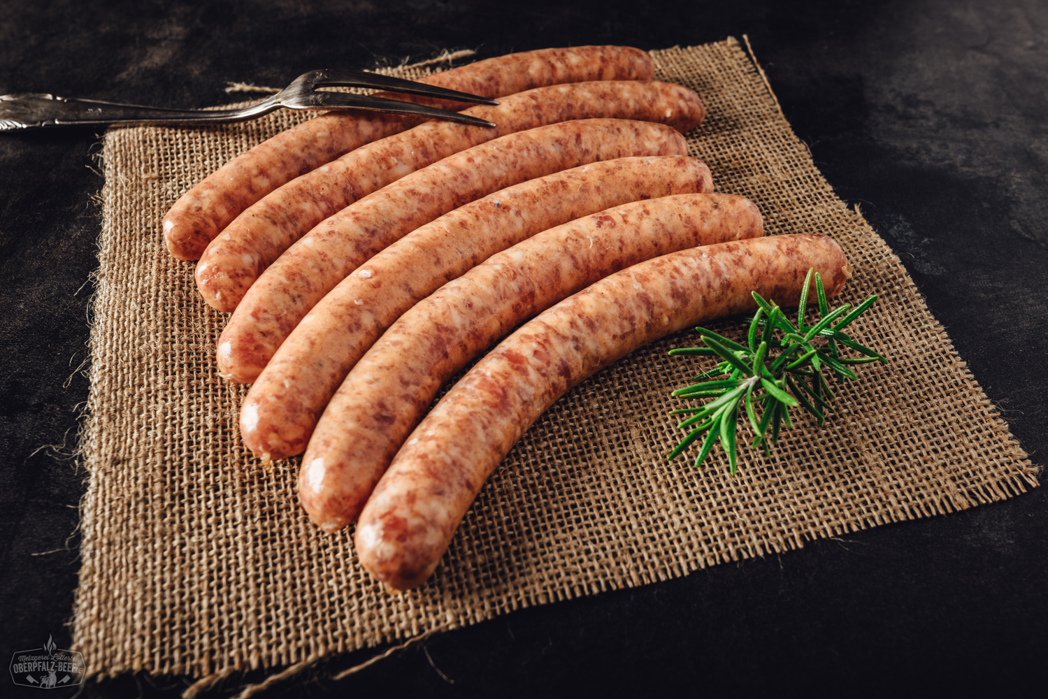 4 Stück salsiccia Bratwürste auf Brett mit aromatischen Kräutern und Gewürzen, perfekte Fleischspezialität für Grill und Pfanne.