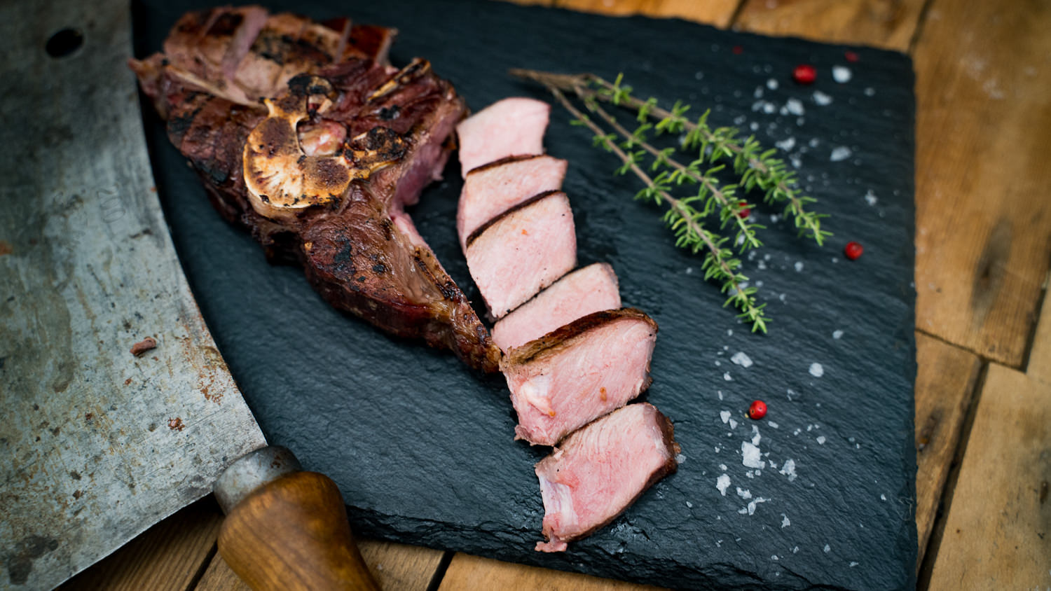 Rücken mit Knochen vom Oberpfälzer Wildschwein auf Holzbrett, nahe Ansicht in natürlichem Licht, saftig und appetitlich, ideal für Wildliebhaber und Grillgenuss.