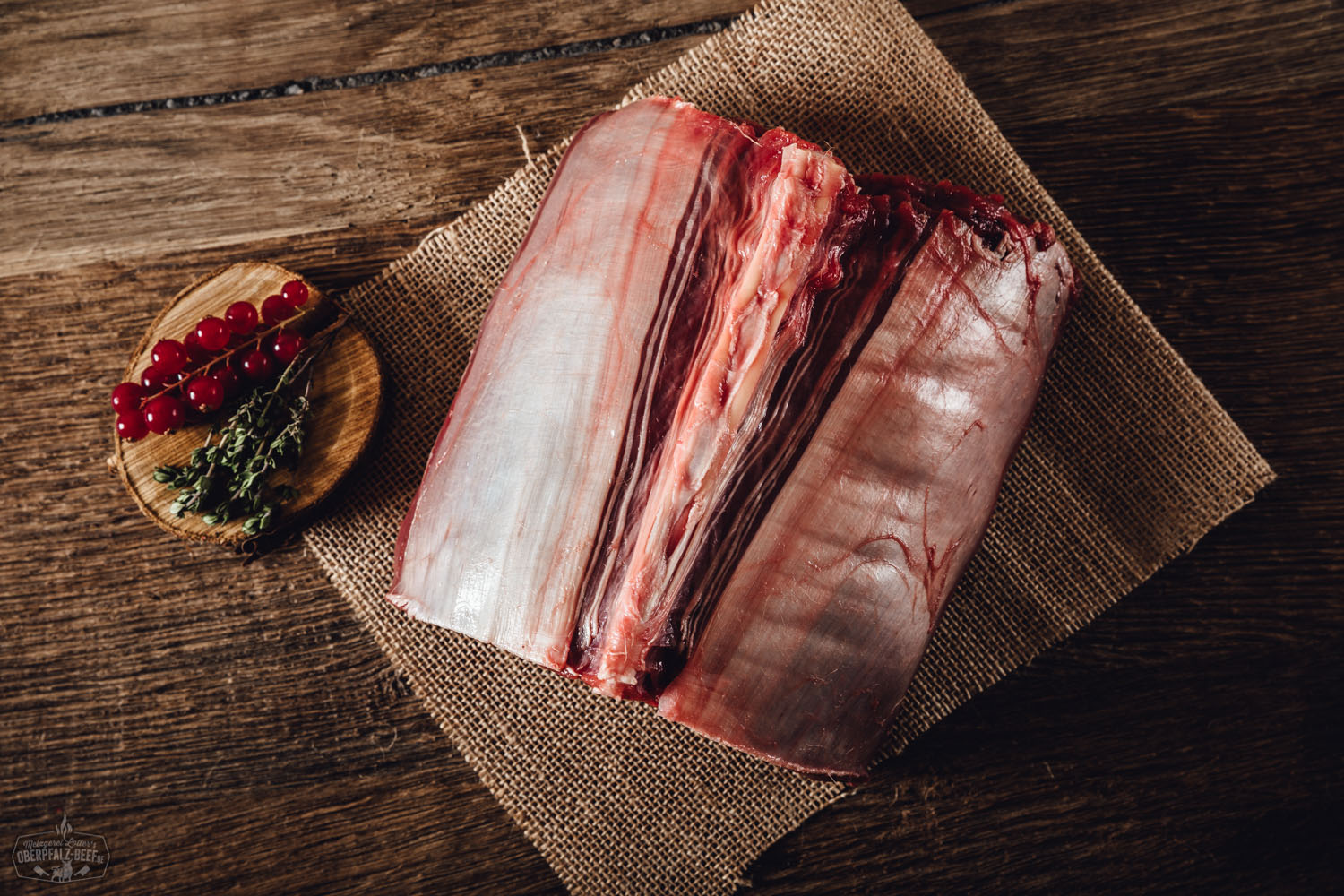 Rücken mit Knochen vom Oberpfälzer Hirsch auf einem Holzbrett platziert. Hochwertiges Wildfleisch aus der Oberpfalz, ideal für Gourmetgerichte und festliche Anlässe. Perfekte Wahl für nachhaltigen Fleischgenuss.