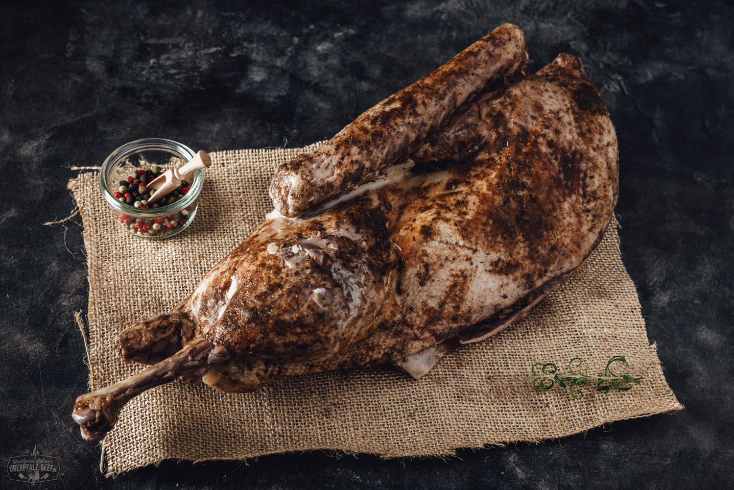 Halbe Sous-Vide vorgegarte Oberpfälzer Bauern Weihnachtsgans auf einem Teller, umgeben von frischen Kräutern und Gewürzen, perfekt zubereitet für festliche Anlässe.