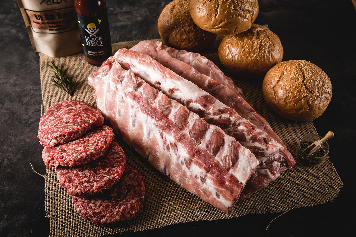 Klassisches Oberpfalz Beef Baby Back Ribs Burger Paket mit saftigen Rippchen und Burger-Zutaten auf einem rustikalen Holzbrett angerichtet