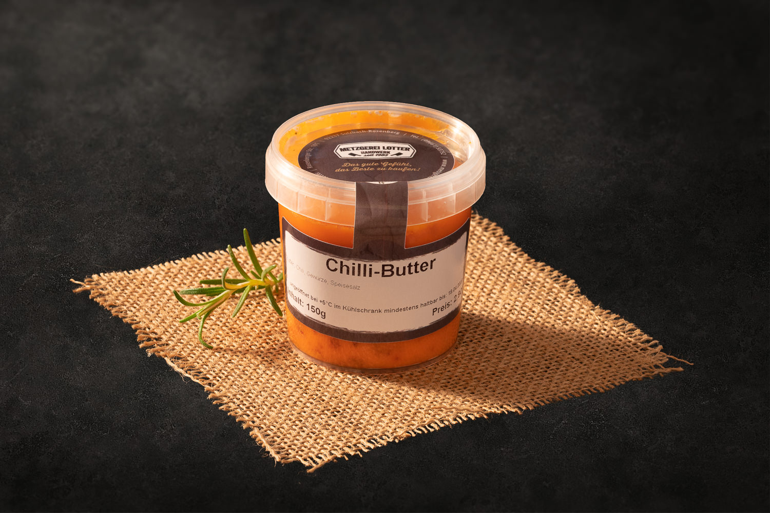 Ein Stück aromatische Chilli-Butter auf einem rustikalen Holzbrett, verfeinert mit Kräutern und Gewürzen, ideal für Grillabende und zum Veredeln von Steaks und Gemüse, fotografiert bei Oberpfalz Beef.