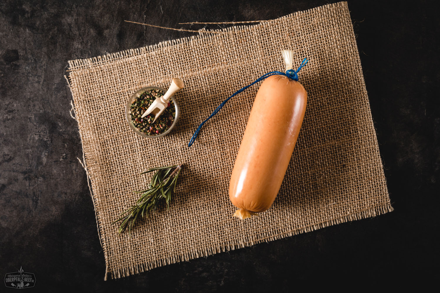 Fein portionierte Mettwurst im Naturdarm, angerichtet auf einem Holzbrett mit frischen Kräutern, perfekt für deftige Brotzeiten und herzhafte Gerichte.