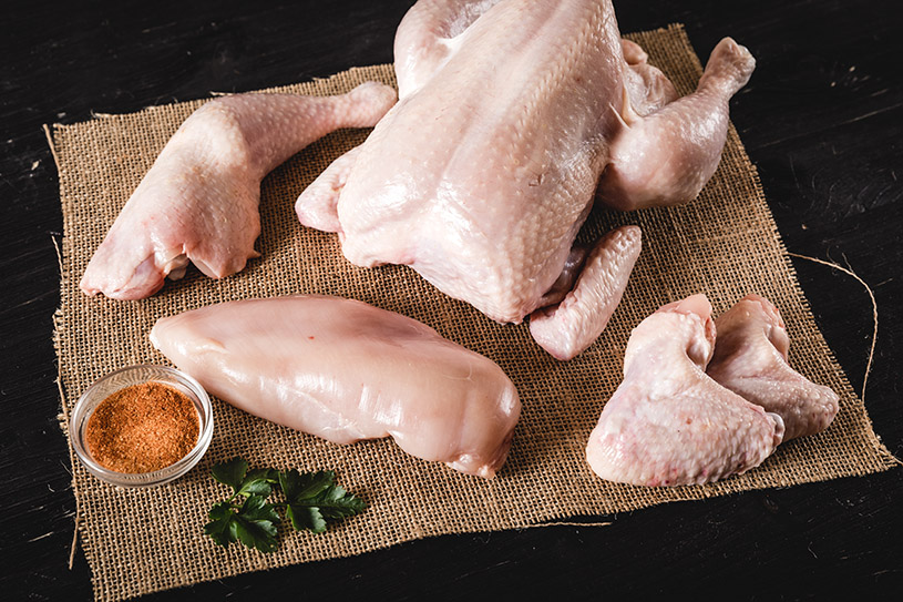 Panoramablick auf eine Auswahl von Geflügelprodukten, darunter Hähnchen- und Entenfleisch, ansprechend angerichtet auf einem rustikalen Holztisch im Hintergrund, ideal zur Bewerbung der Produktvielfalt von Oberpfalz Beef.